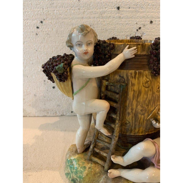 Polychrome porcelain group Three putti harvesting grapes around a barrel Bears a blue mark under the base Good condition...