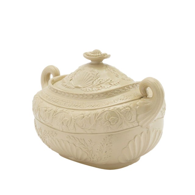 A stoneware sugar bowl in a putty color with fine smear glaze. The double pistol grip handles flank the impressed floral...