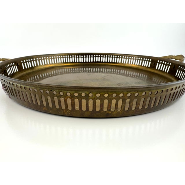 Vintage brass serving tray with a pierced gallery rim and decorative cast handles. The wide circular form is accented by...