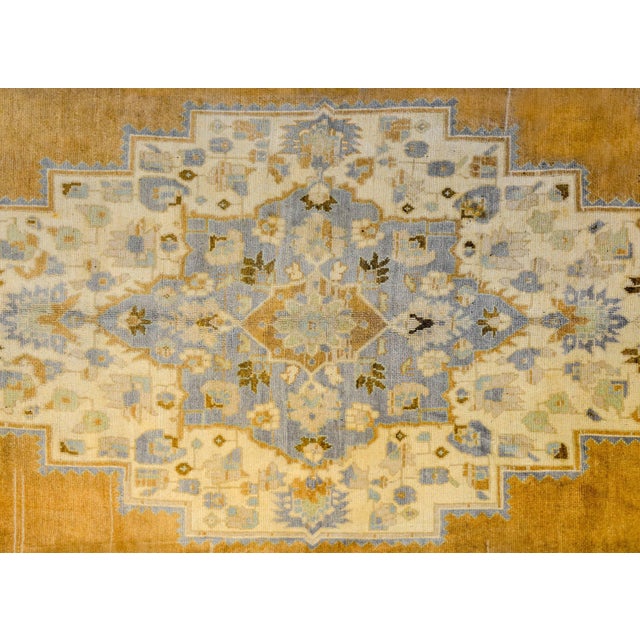 A vintage Turkish Oushak rug with a beautiful diamond medallion amidst a field of flowers woven in gold, indigo, brown,...