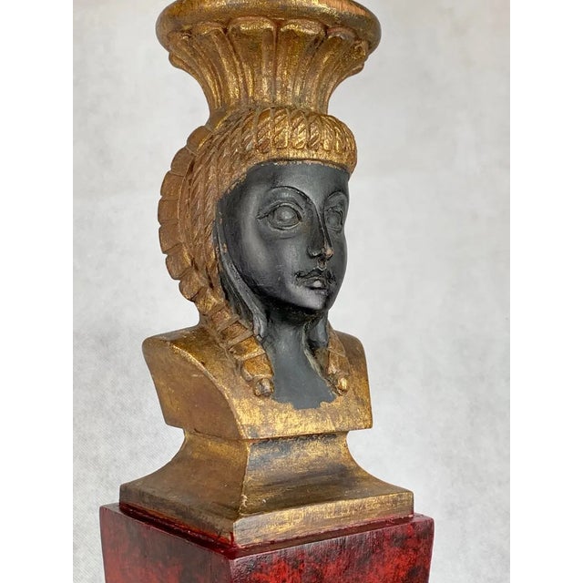 Egyptian revival carved wood lamp. The chiseled feminine ebonized face is surmounted by a gilt headdress. The body of the...