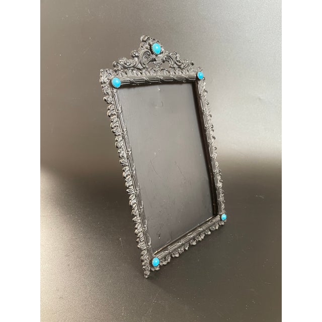 An antique photo frame from the late Victorian era, featuring an intricate bezel design with vines wrapping around the...