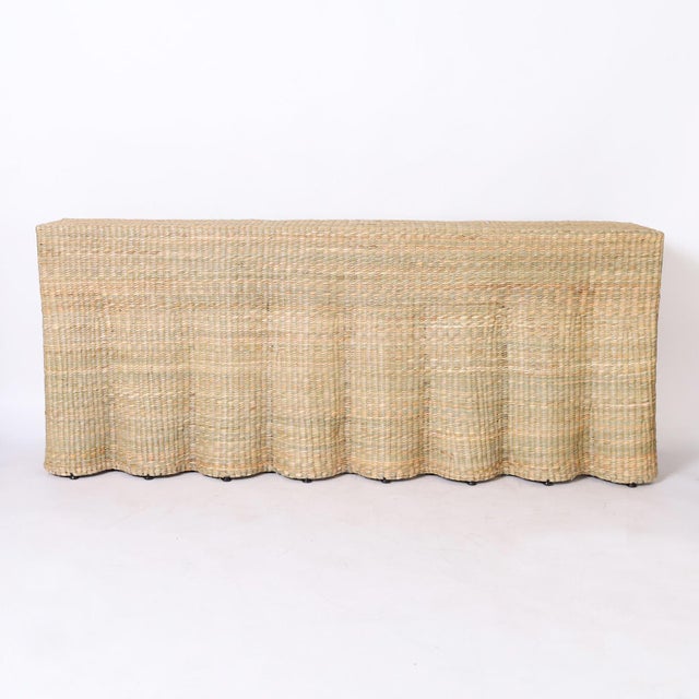 An in vogue long ghost drapery console hand crafted with a durable metal frame wrapped in reed with a desirable slim...