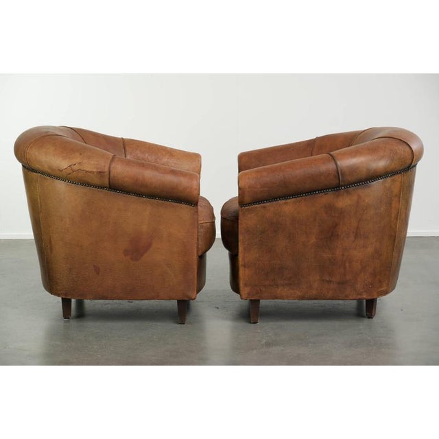 This rugged set of vintage sheepskin club chairs has a beautifully weathered look and is finished with decorative studs....