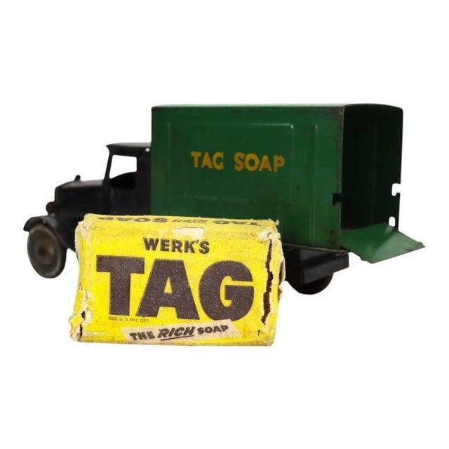 An antique pressed steel toy truck, likely dating to circa 1920. The truck features a black cab and chassis with a...