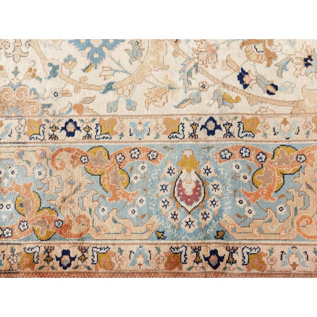 An early 20th century Persian Tabriz antique rug, the cream field with an overall design of scrolling leafy arabesques,...