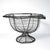 A striking vintage hand-worked wire pedestal basket in the French country tradition, featuring an unusually sculptural...