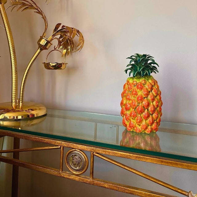 A striking glazed ceramic pineapple sculpture. The glossy orange, yellow and green glaze gives the piece a vivid,...