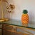 A striking glazed ceramic pineapple sculpture. The glossy orange, yellow and green glaze gives the piece a vivid,...