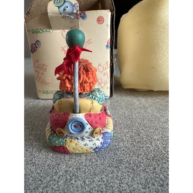 This is a charming Enesco figurine from the 'Cute as a Button' collection, featuring a whimsical character in a colorful...