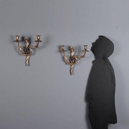 Pair of burnished bronze wall lamps. Two lights supported by leaf-shaped arms with Rocaille movements. Italy, XX century....