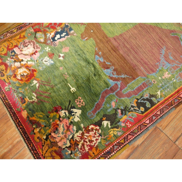 A happy deer on a green field and floral background on this lovely russian karabagh rug from the 1920's. Full Pile condition