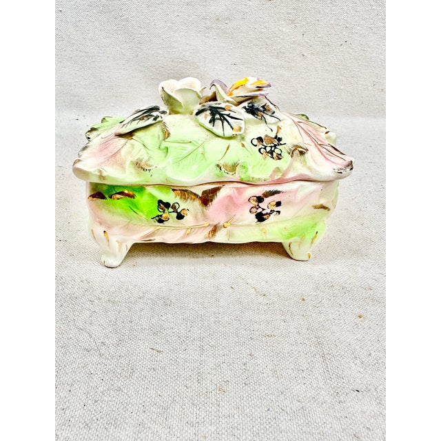 Beautiful vintage ceramic box. Features a floral design in pink and green with gold accents. Perfect to use for small...