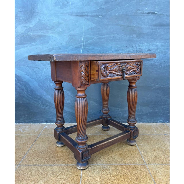 Spanish Renaissance Revival side table crafted in solid oak, Early-20th century. The table features a richly carved drawer...