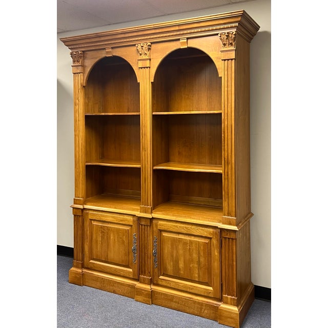 Ethan Allen Legacy double-arch bookcase features classic fluted pilasters, Corinthian-style carved capitals, and two lower...