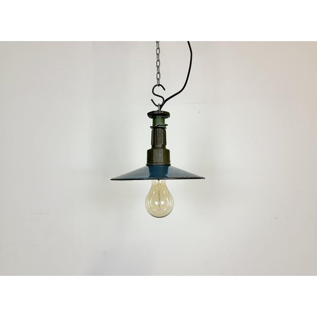 Industrial blue enamel pendant light made in Poland during the 1960s. White enamel inside the shade. Green cast aluminium...