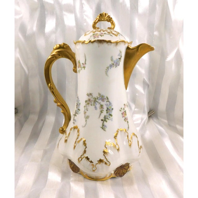 This is an L Straus and Sons Limoges Chocolate Pot that is dated 1890 to 1920. It is white with blue and pin k flowers...