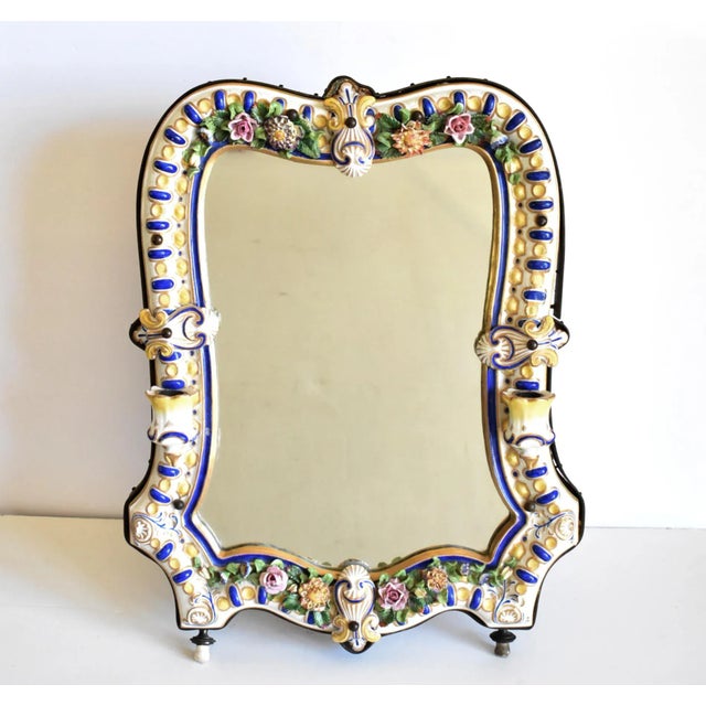 An antique, German porcelain mirror with a blue, yellow, and gold design on a white background, with delicate flowers, and...