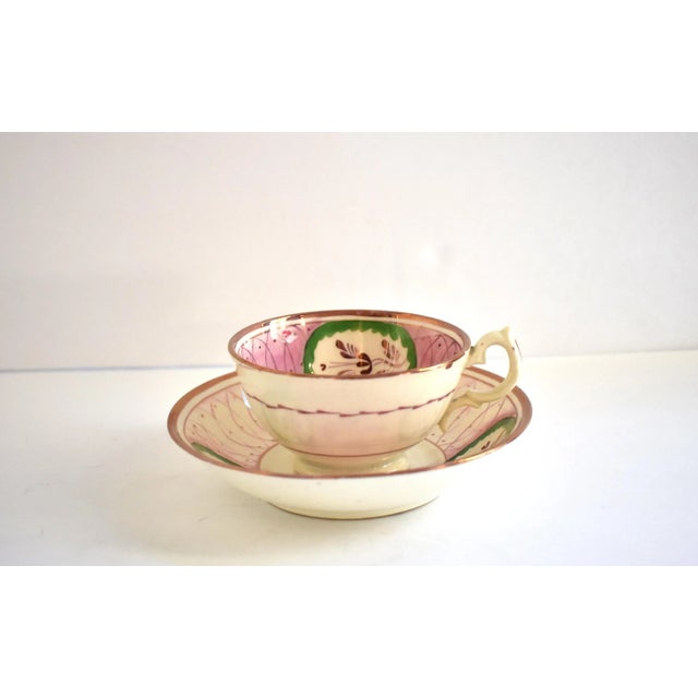 An antique, Georgian, early 19th-century c. 1820-1830 Staffordshire creamware soft paste footed teacup and saucer, in pink...