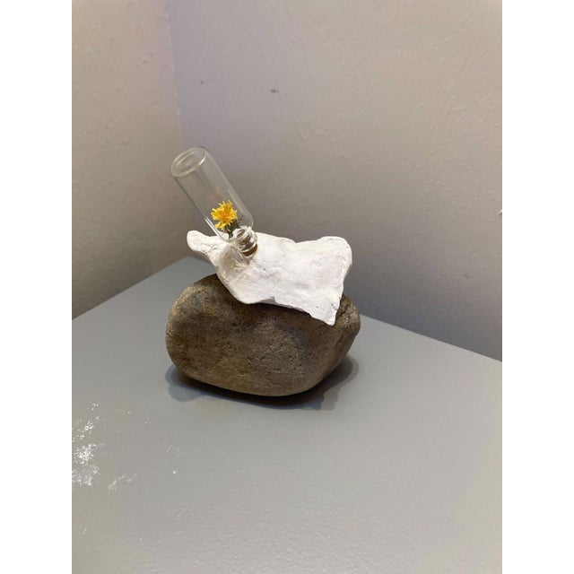 Secret's Safe features a delicate composition of mixed media, showcasing a small glass vial containing a bright yellow...