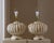 Striking matched pair of vintage table lamps featuring sculptural woven rattan bodies in an aged ivory finish. The...