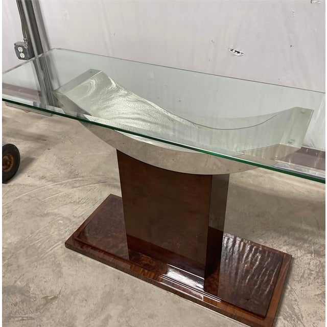 This stunning console table is elegant and architectural. It features a sleek rectangular glass top resting on a dramatic...