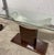 This stunning console table is elegant and architectural. It features a sleek rectangular glass top resting on a dramatic...