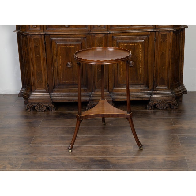 An English Regency period mahogany guéridon table from the early 19th century, with pie crust tray top, tripartite shelf...