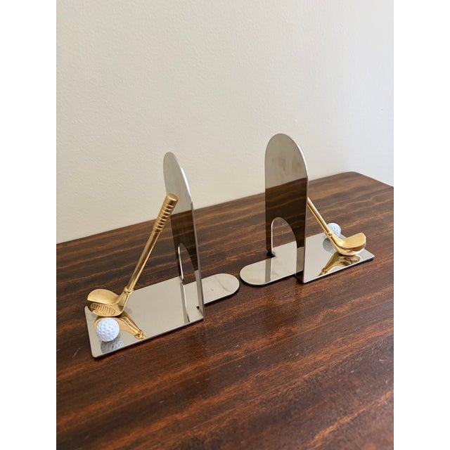 A beautiful pair of cast brass bookends in the form of golf clubs and golf balls. Circa 1980s Measures: 5.5"W x 2.63"D x...
