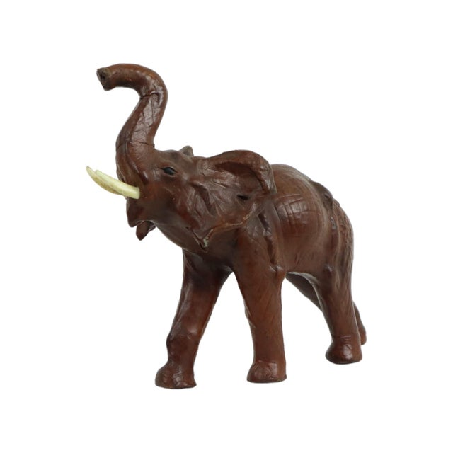 Charming vintage papier-mâché elephant figure covered in brown leather, featuring synthetic tusks; dates from...
