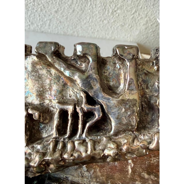 N. Levi (signed in Hebrew and English) Menorah Done in a brutalist design with the Hebrew words "Seek the peace of...
