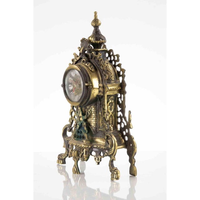 Ancient Victorian table clock, round clock face with Roman numerals and decorative hands, protected by a glass cover. A...