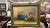 A classic still life oil painting depicting a vibrant blue bowl with fruit, apples, dark grapes, and a glass of red wine...