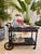 Elegant black metal bar cart featuring intricate scrollwork details and timeless Palm Beach sophistication. Beautifully...