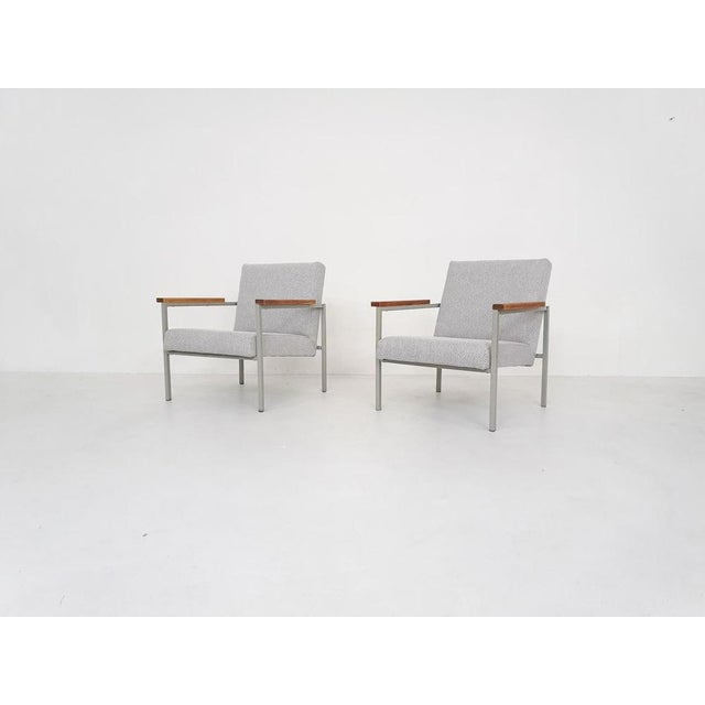 Grey metal frame and teak arm rests. We have re-upholstered them in new grey-white fabric. The design reminds us of Rob Parry