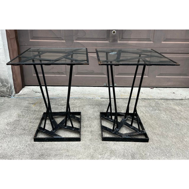 Pair of brutalist style, hand wrought iron outdoor side tables. Unique, one of a kind. Bases are painted black and feature...