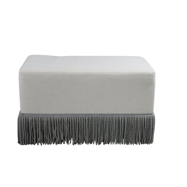 Rectangular linen upholstered ottoman by Restoration Hardware. Features twisted tassels along the base. Circa 2024...