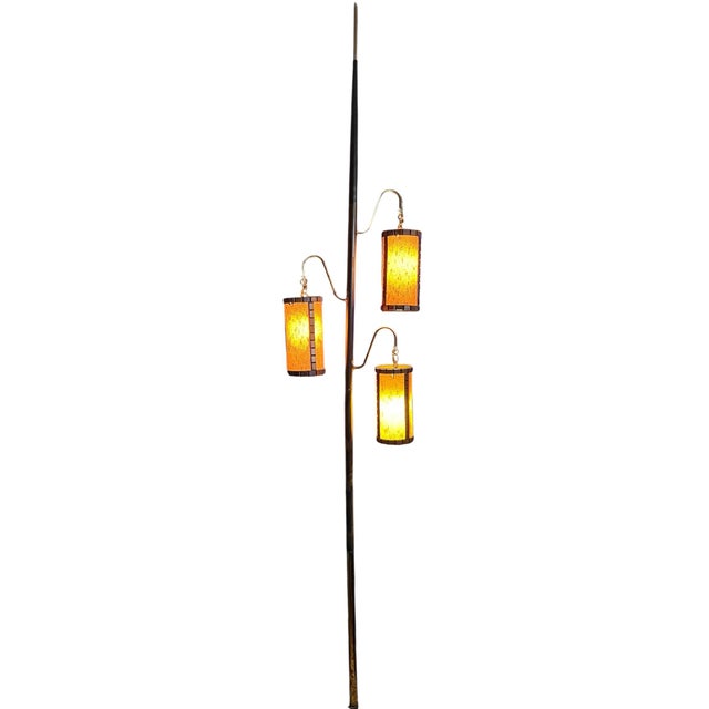 This striking 1960s mid-century modern tension pole lamp features three glowing amber lantern-style shades suspended from...