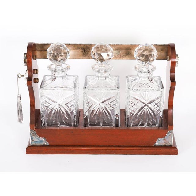 An attractive English silver plate mounted mahogany three bottle tantalus by Puddefoot, Bowers & Simonett Ltd, late 20th...
