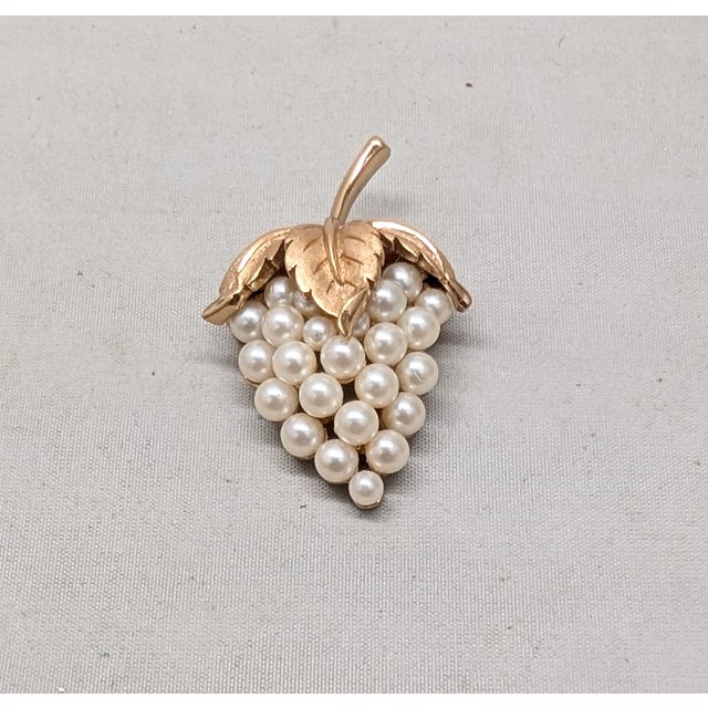 1960s goldtone textured leaf top with faux-pearl "grapes" bottom brooch with security clasp. Marked crown "TRIFARI©" on...