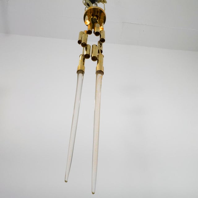 Sculptural brass flush mount ceiling light composed of cascading brass cylinders with cylindrical "icicle" elements.