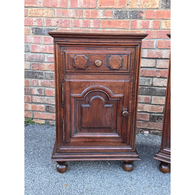 This is a pair of antique French bedside tables crafted from dark stained oak. They are lovely and adorned with carved...