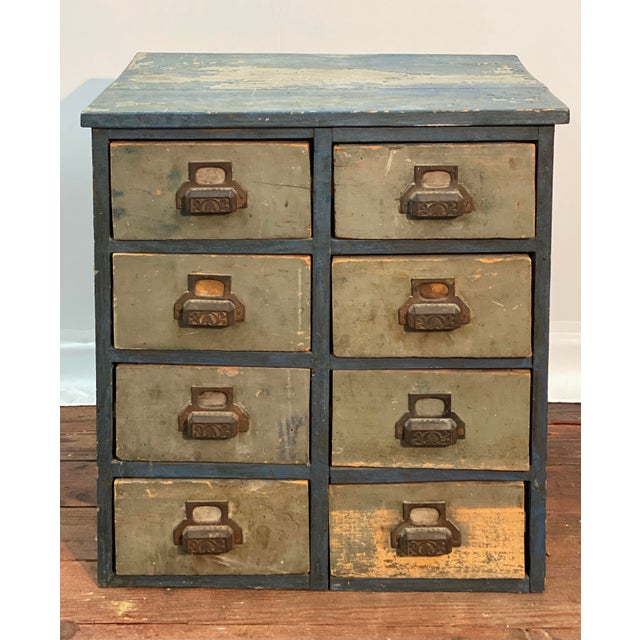 A nicely distressed and weathered workshop parts cabinet. Circa 1920-1930. The case is painted and the blue paint has a...