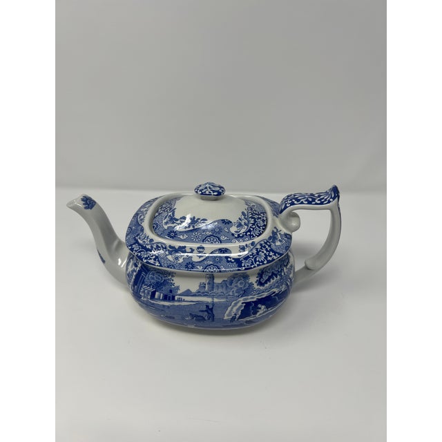 A classic blue-and-white Spode “Italian” pattern teapot, made in England and featuring the brand’s iconic pastoral...