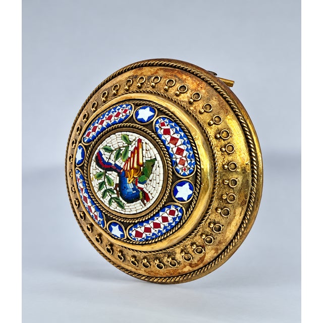 This round object is an ornate piece of Victorian-era micromosaic jewelry or decorative ware, likely Italian in origin. It...