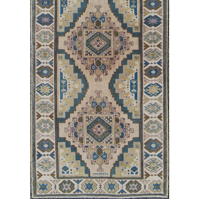 This vintage Turkish Oushak runner (circa 1930) features a unique blend of colors and an intricately beautiful design. The...