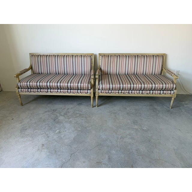 Beautiful pair of vintage French Neoclassical style settees, showcasing clean lines and elegant carved details throughout....
