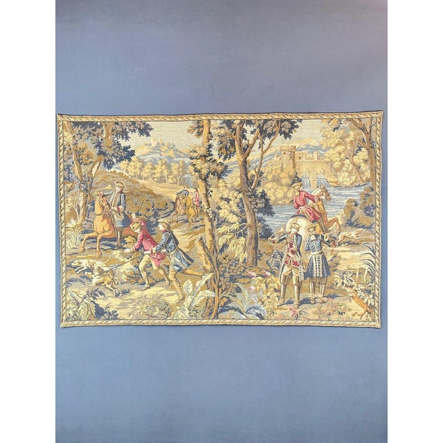Magnificent wall tapestry depicting a hunting scene in a wooded, hilly landscape, with riders, hounds, and elegant figures...