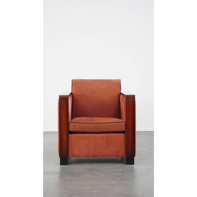 Luxurious Art Deco design armchair with red fabric upholstery and wooden details. This sleek and luxurious armchair is a...