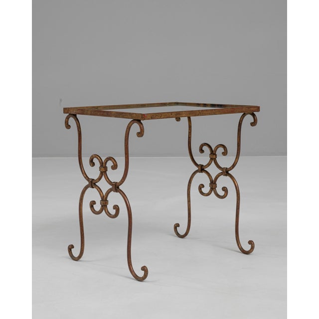 This 20th Century French brass coffee table features an elegant silhouette defined by its finely scrolled ironwork-style...
